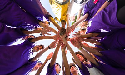 Group of people putting their hands in the middle of a circle, worm's eye view