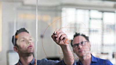 Engineers drawing diagram on glass wall