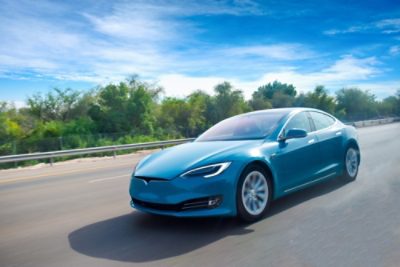 A blue colored electric car cruising on highway