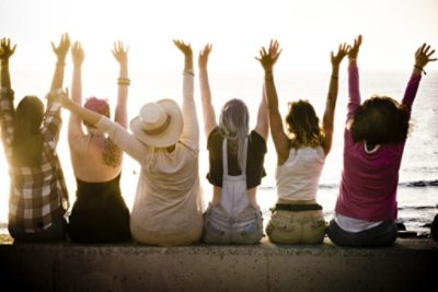 rear view of group of friends enjoying at the sunset with ocean in background