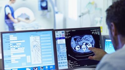 Male doctor running CT scan from control room at hospital