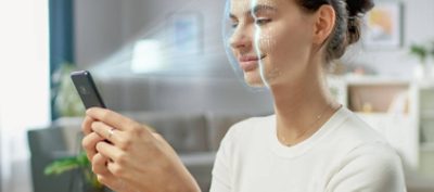 Young Female Identified by Biometric Facial Recognition Scanning Process from Her Smartphone. Futuristic Concept: Projector Identifies Individual by Illuminating Face by Dots and Scanning with Laser